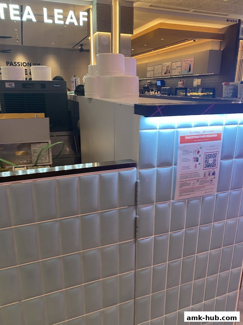 A counter area with stacked white cups and a sign on the wall.