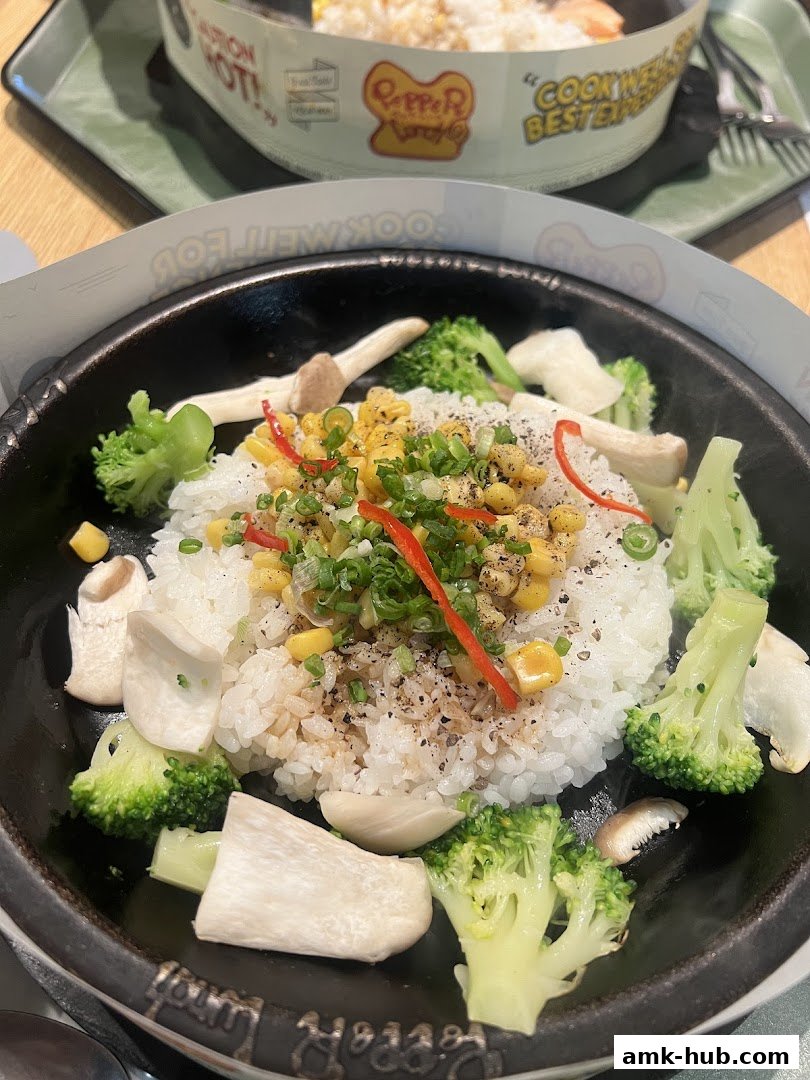A sizzling hot plate of rice with broccoli, mushrooms, corn, and chili.