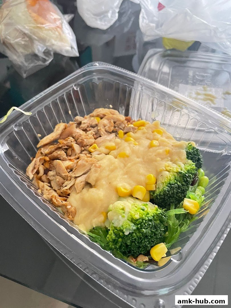 A takeout container filled with a healthy meal of chicken, mashed potatoes, corn, and broccoli.