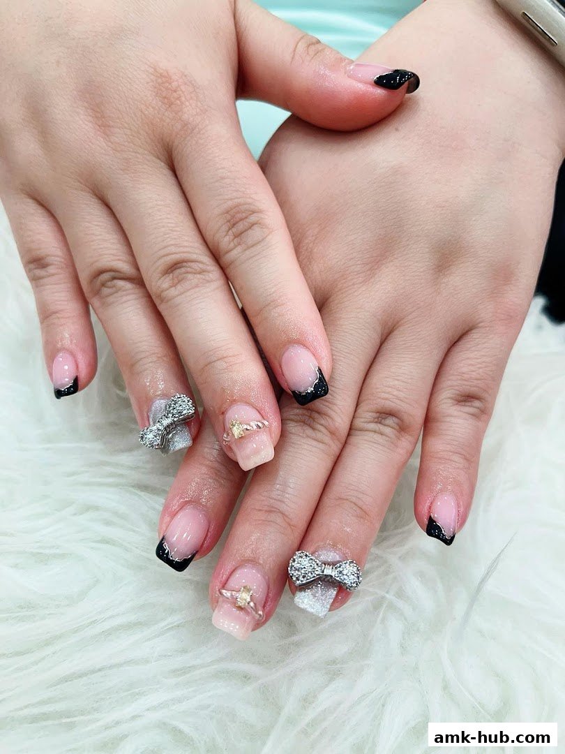 Close-up of hands with elaborate French manicures featuring bows and ring embellishments.