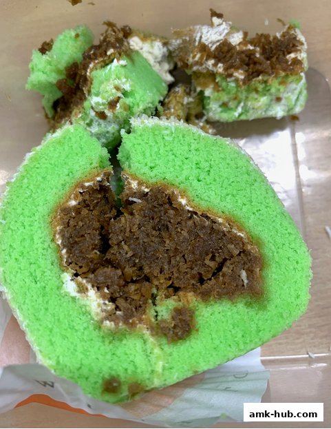 A close-up of a sliced green swiss roll cake with a brown filling.