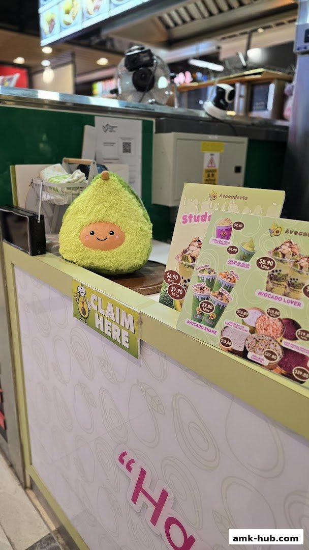 A counter at Avocadoria with a plush avocado toy and a menu displaying avocado drinks and desserts.