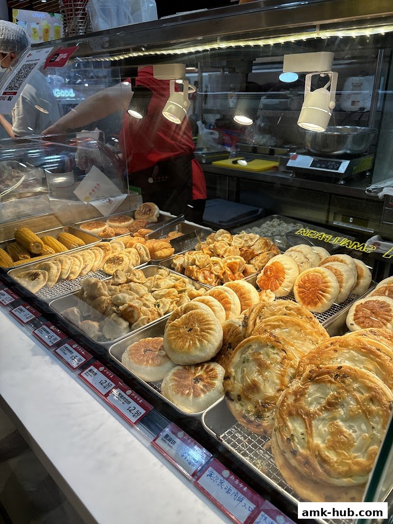 A display case filled with various freshly baked savory pastries and corn on the cob.