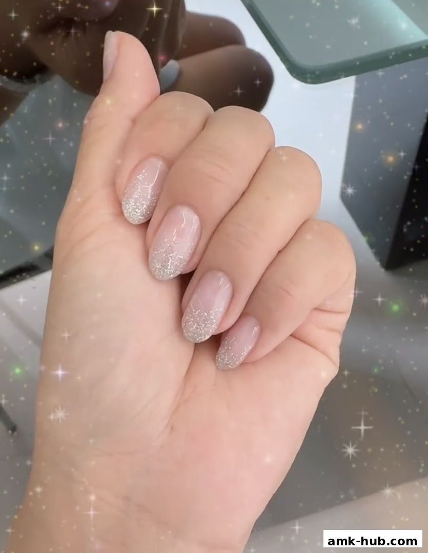 A close-up of a hand with elegant, glitter-accented nails.