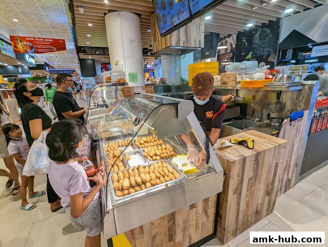 A food stall with a variety of fried snacks displayed in a refrigerated case.