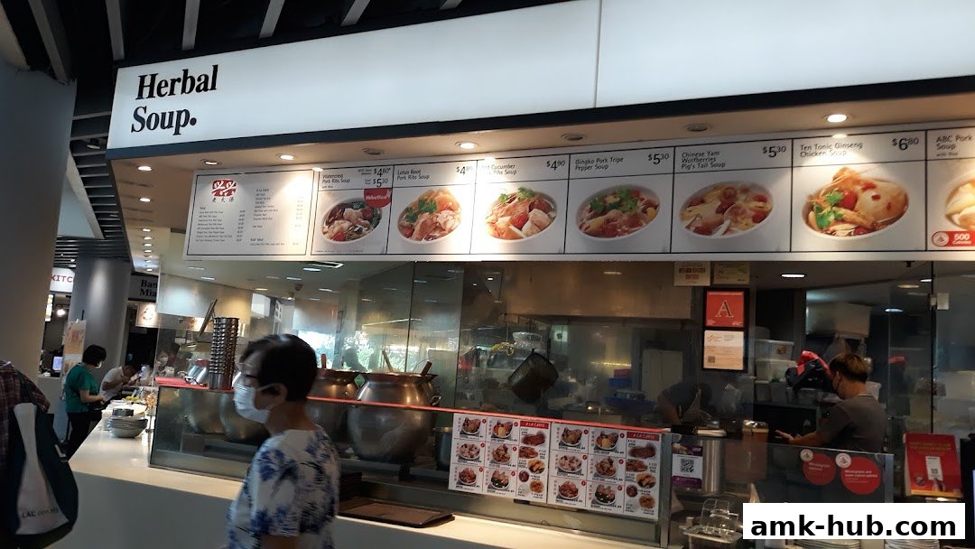 A food stall counter displaying various herbal soups with prices and images.