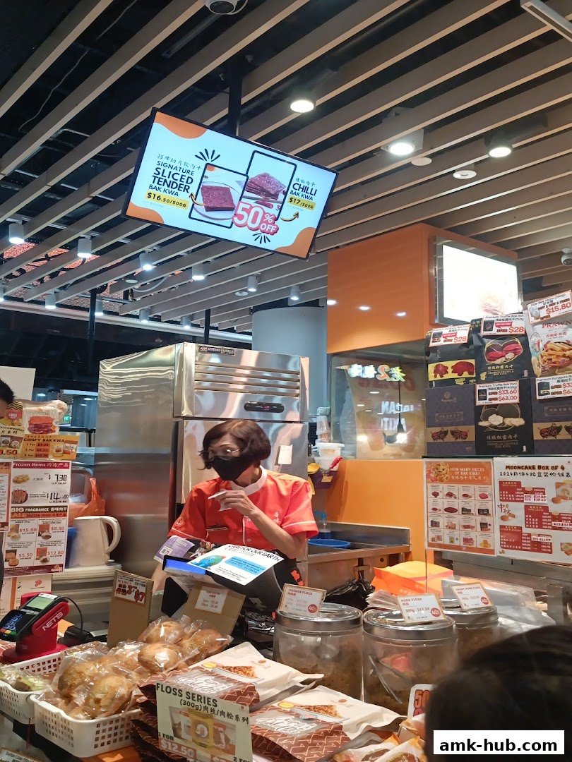 A shop counter with a staff member and various bak kwa products displayed.