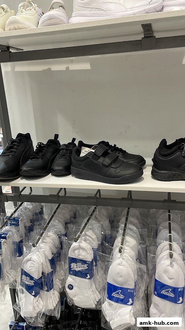 A display of black athletic shoes and white socks on shelves in a retail store.