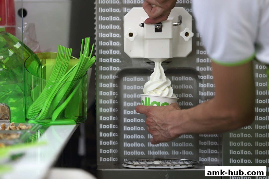 A person is dispensing frozen yogurt into a cup from a machine.