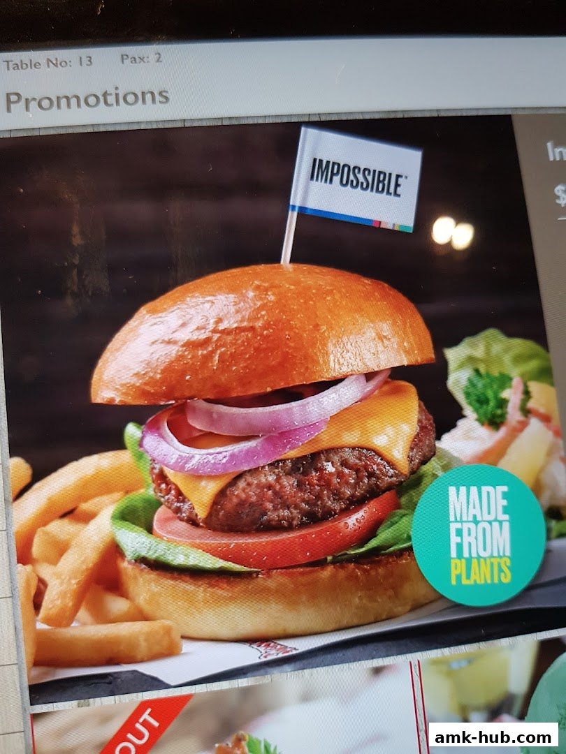 A delicious Impossible burger with fries and a side salad, featuring a "Made From Plants" label.