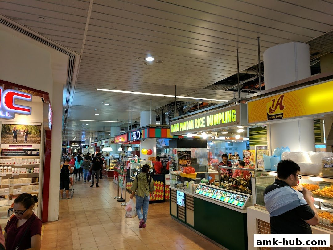 A busy food court with various stalls, including Daun Pandan Rice Dumpling.