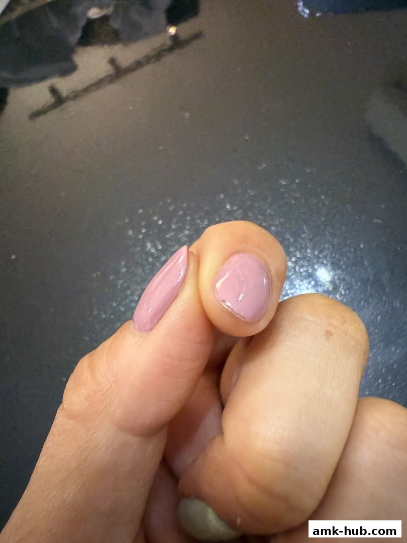 A close-up of a hand with light pink nail polish, showing a chipped nail.