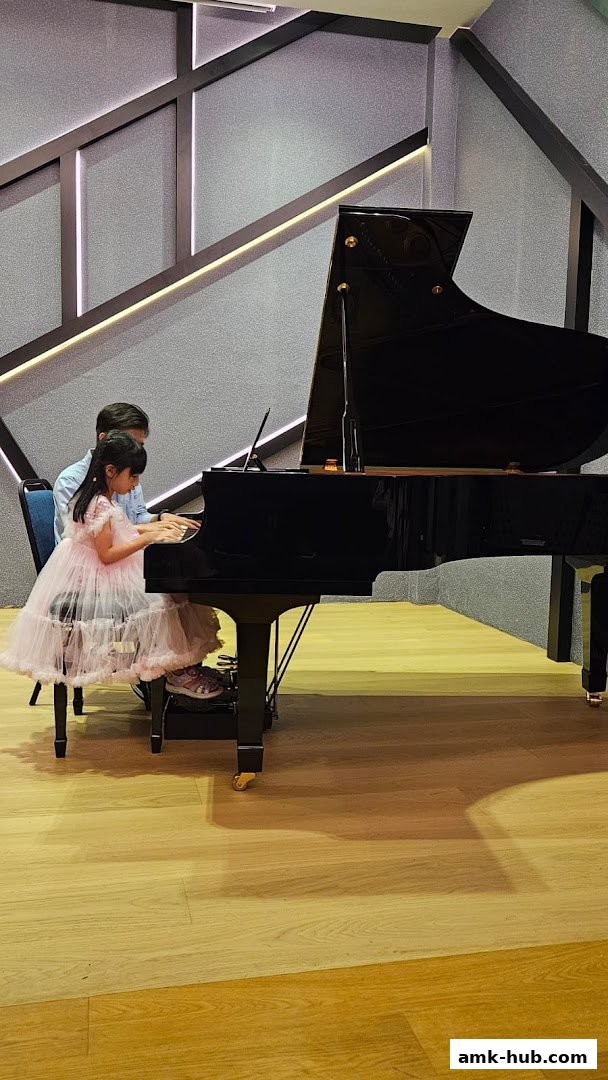 A young girl in a pink dress receives piano lessons from an instructor.
