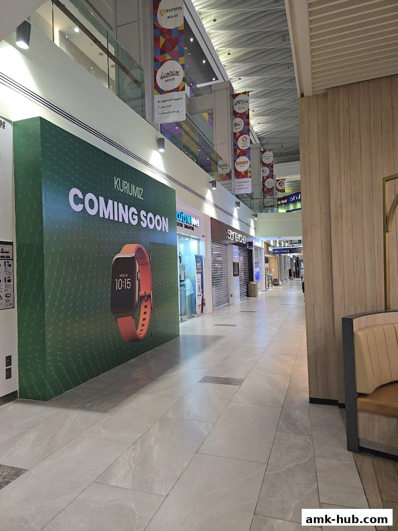 A shopping mall corridor with various shop fronts and a large 'Coming Soon' advertisement.
