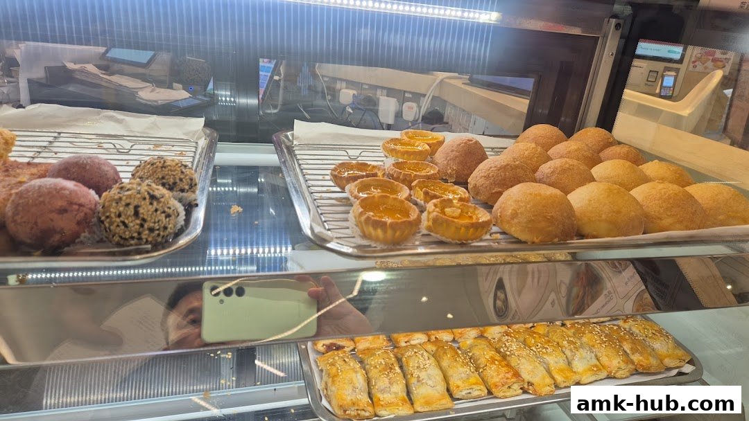 A display case filled with various dim sum and pastries, including tarts, buns, and savory rolls.