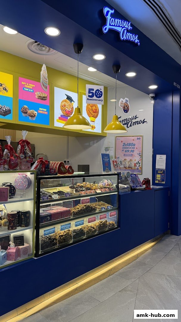 A Famous Amos cookie shop counter displaying various cookies, muffins, and gift boxes.