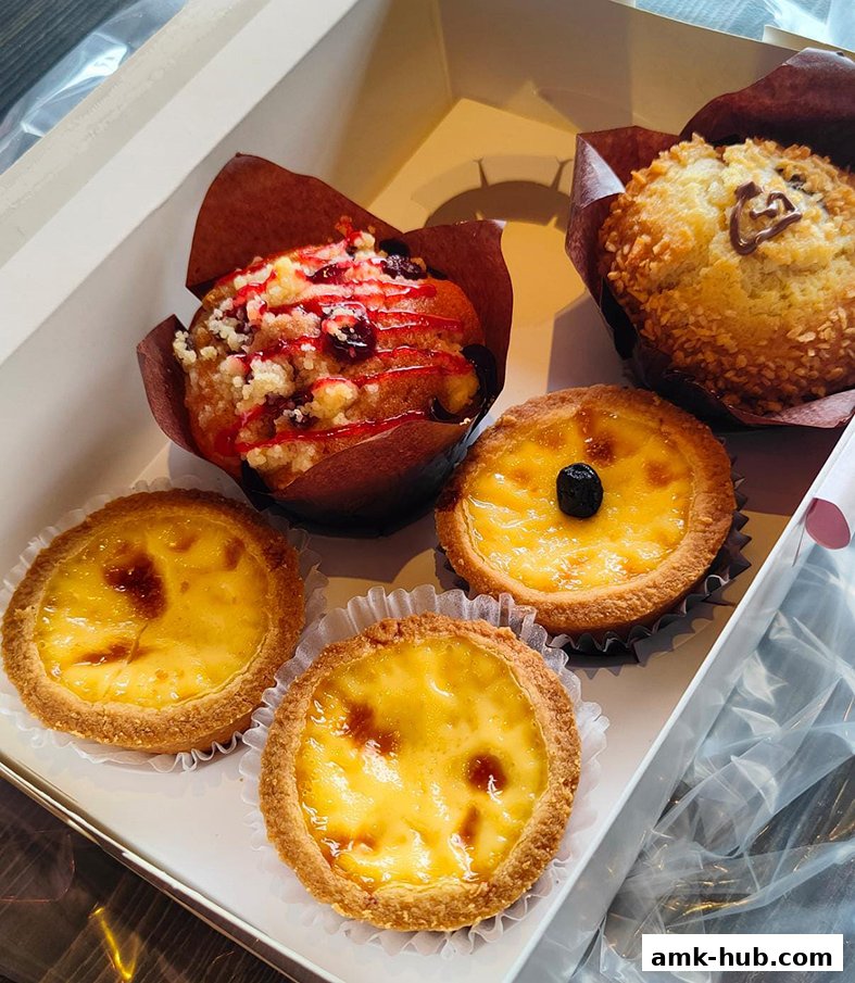 A box filled with freshly baked muffins and egg tarts, ready for enjoyment.