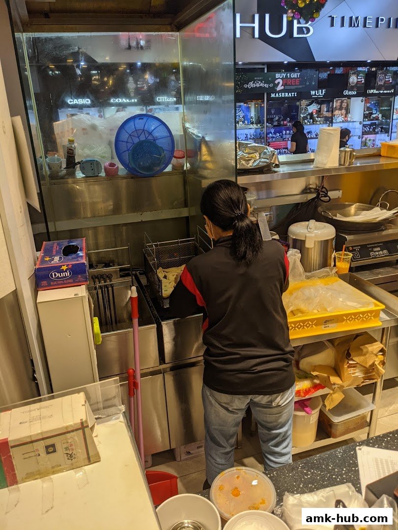 A person is cooking in a kitchen with various appliances and ingredients visible.