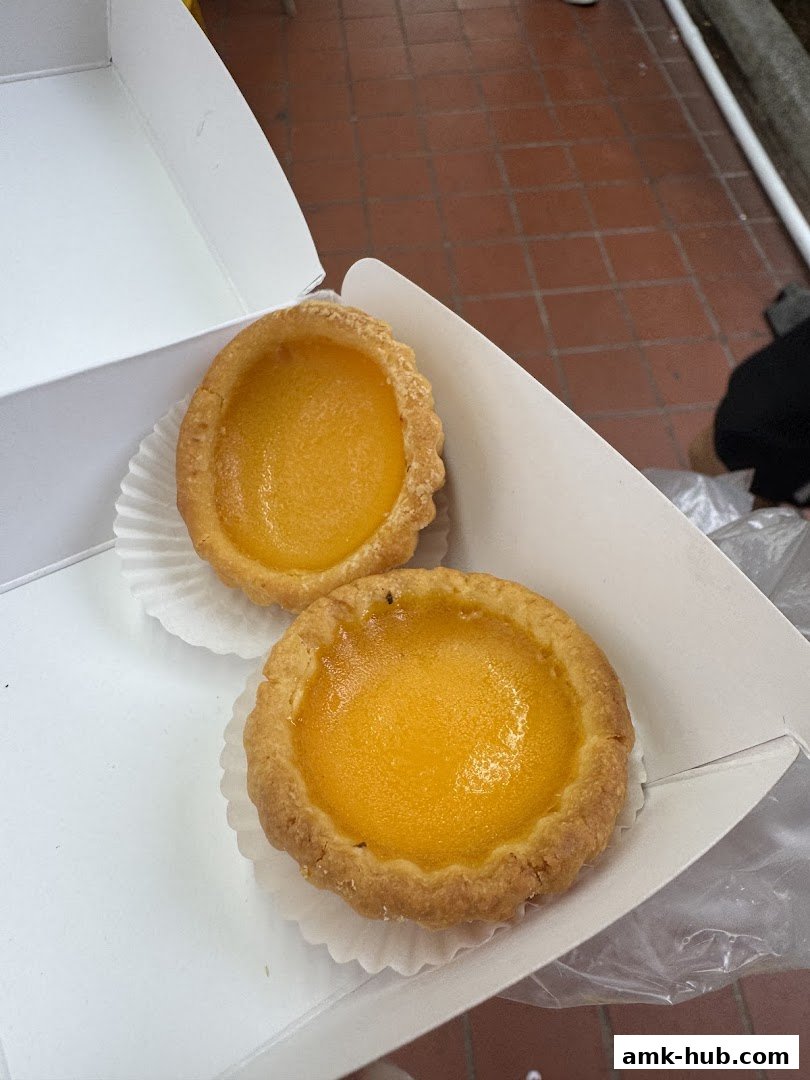 Two delicious-looking egg tarts in a white box, ready to be enjoyed.