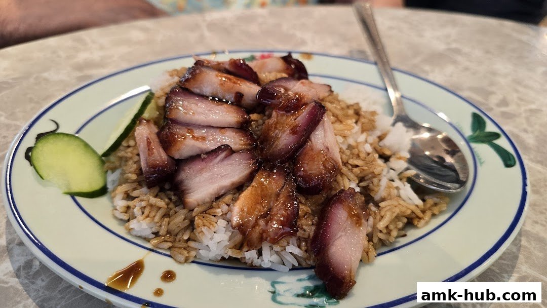 A plate of char siu (barbecued pork) served with rice and cucumber slices.