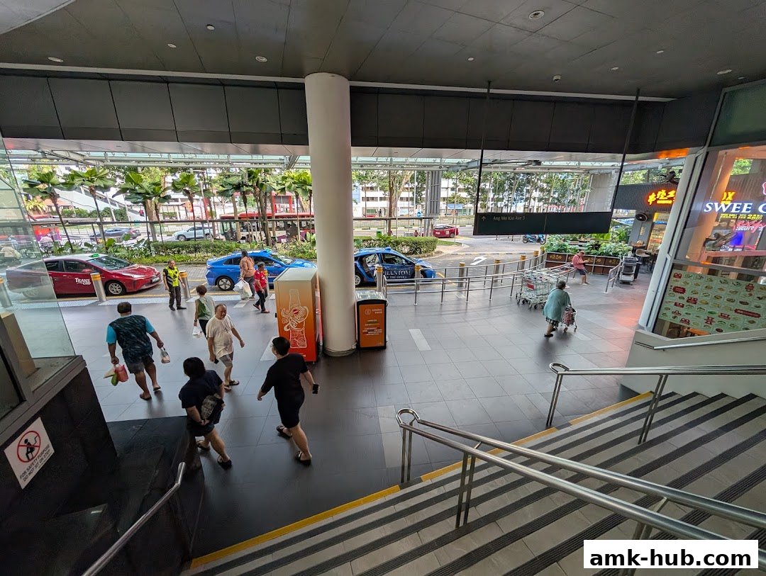 People walking near a taxi stand and a shop entrance with a menu displayed.