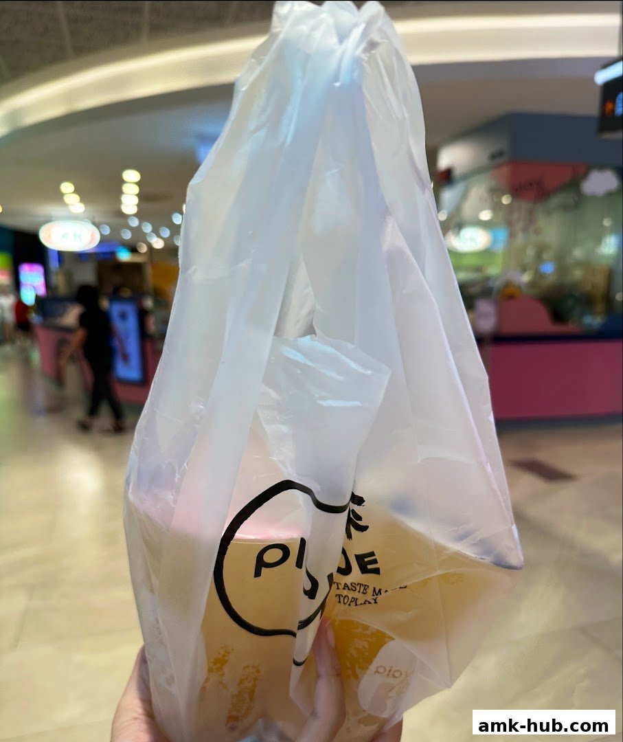 A hand holds a plastic bag with two drinks from Playground by PlayMade.