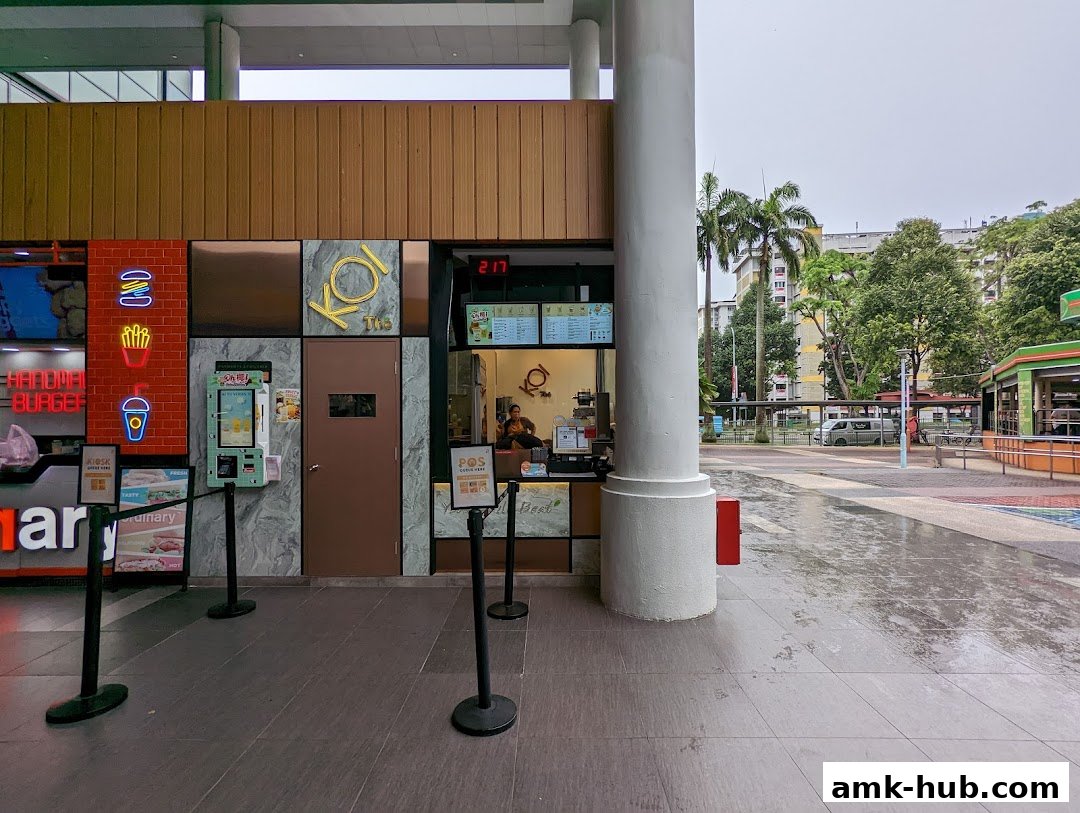 The KOI Thé shop front with neon burger, fries, and drink signs and a POS system.
