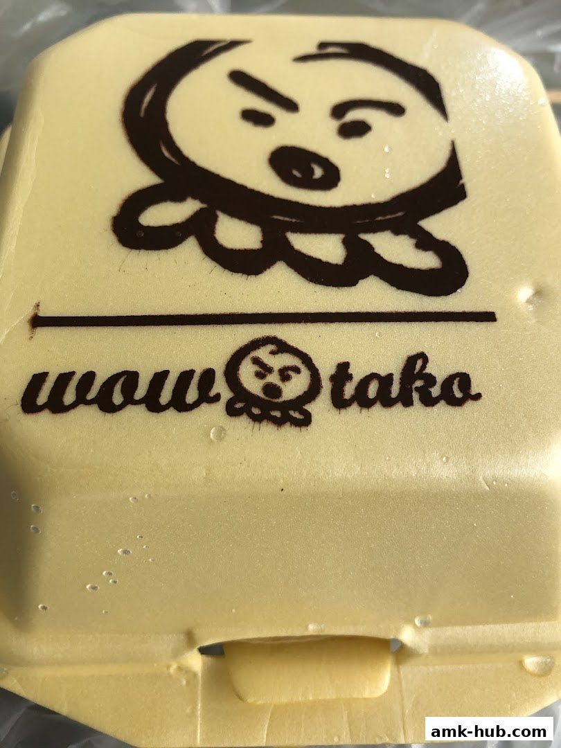 A close-up of a yellow food container with the 'Wow Tako' logo and a cartoon octopus character.