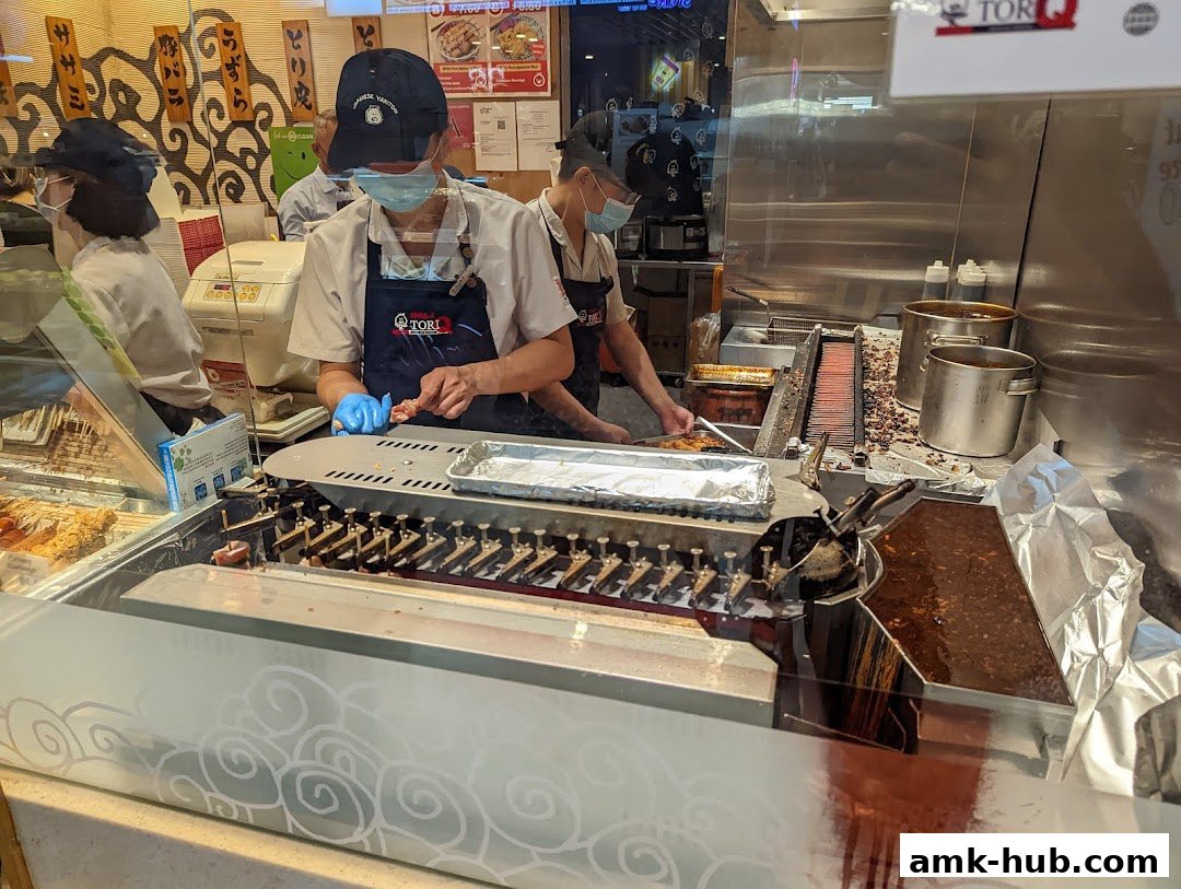 Staff preparing skewers at a Japanese yakitori restaurant counter.