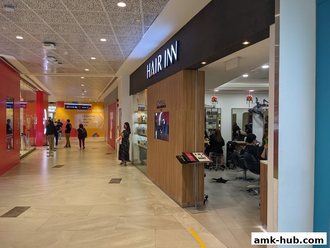 The entrance to Hair Inn, a salon with stylists working inside, located in a mall.