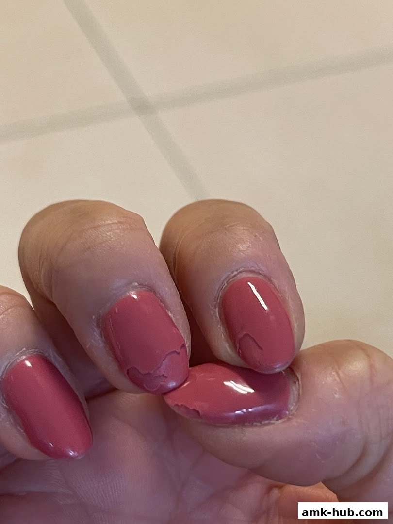 Close-up of a hand with chipped pink nail polish on several fingers.
