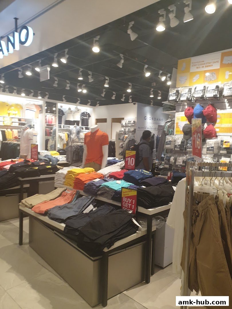 Interior view of a Giordano clothing store showcasing folded shirts and pants on display tables.