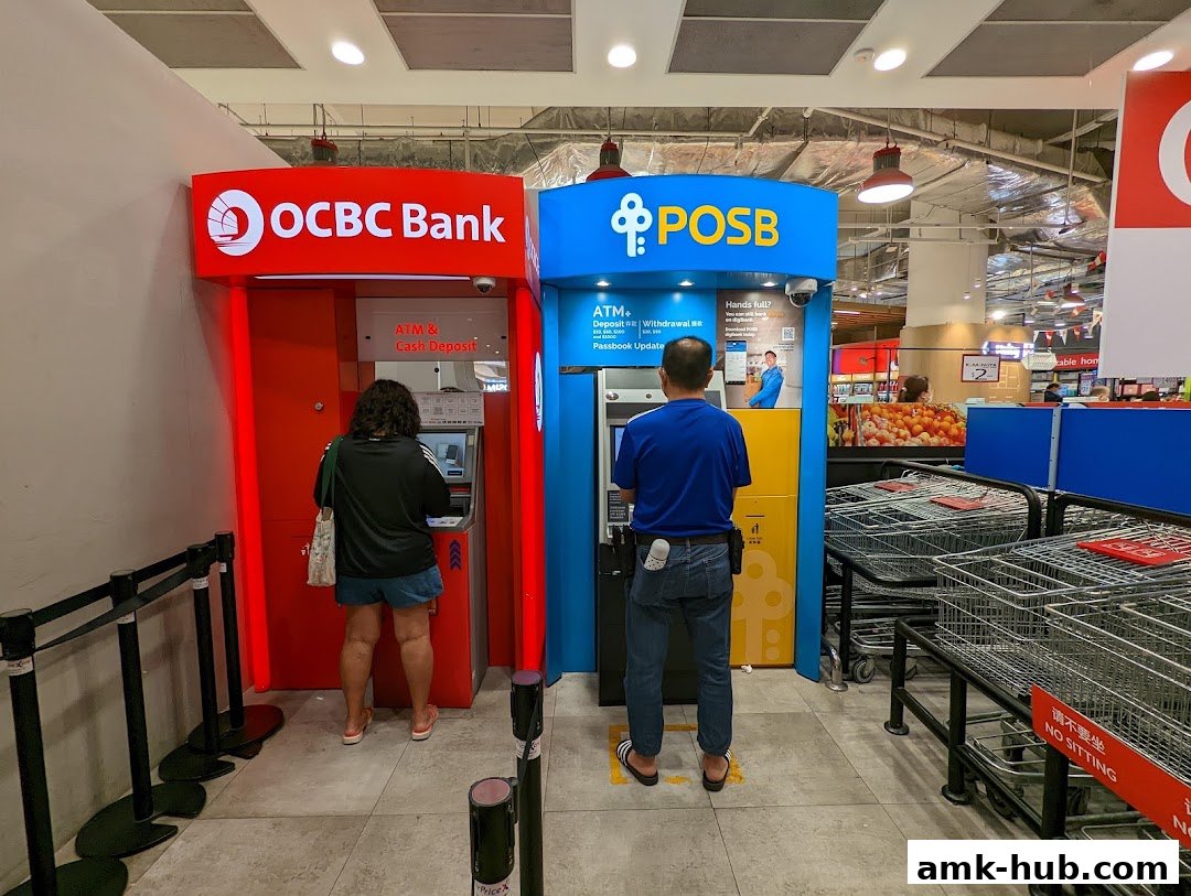 Two people using OCBC and POSB ATMs inside a Fairprice Xtra supermarket.