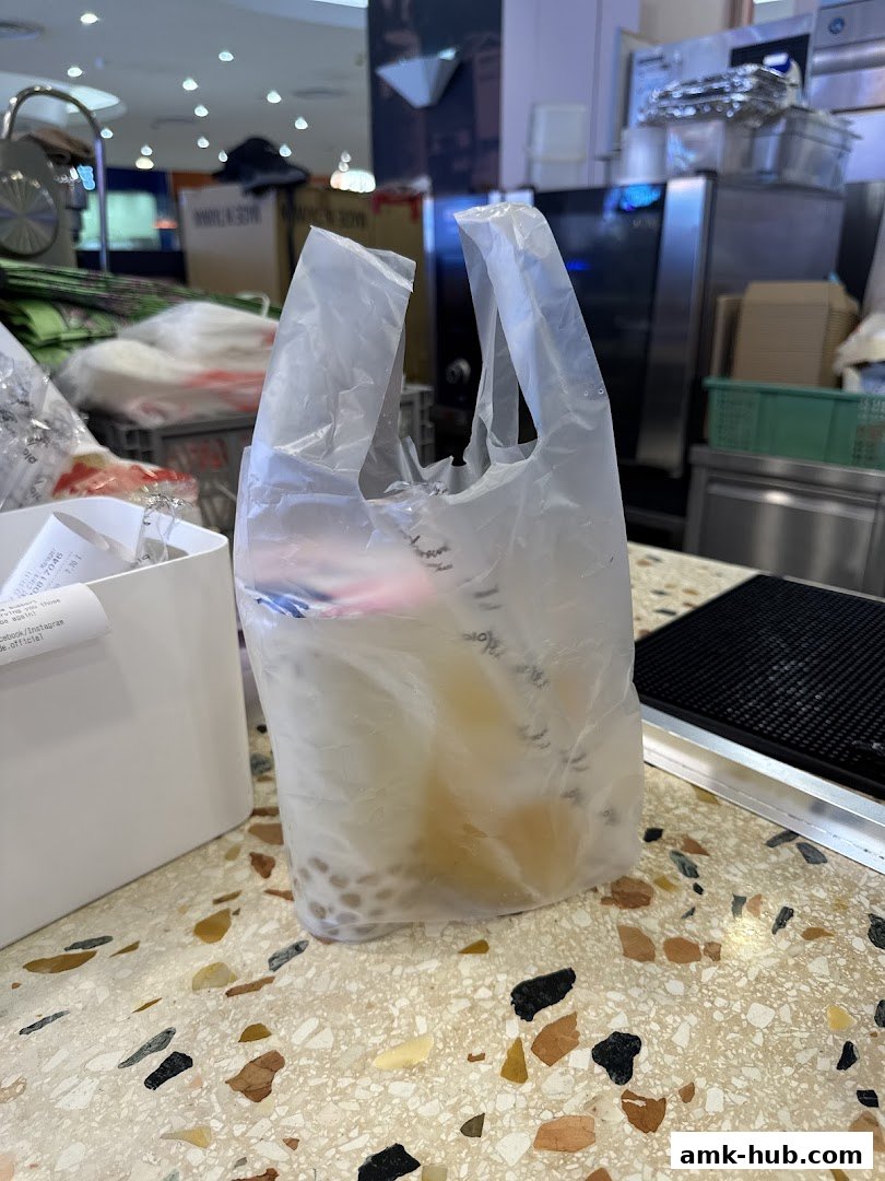 A plastic bag filled with drinks and boba pearls sits on a speckled countertop.
