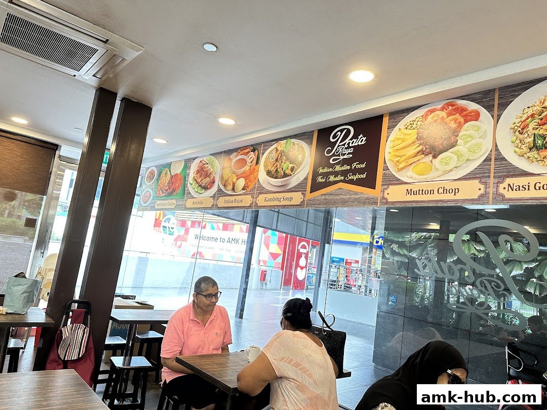 Interior of Prata Raya restaurant with customers and food displays on the wall.