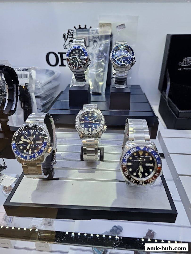 A display of various Seiko automatic watches with metal bands and colorful bezels.