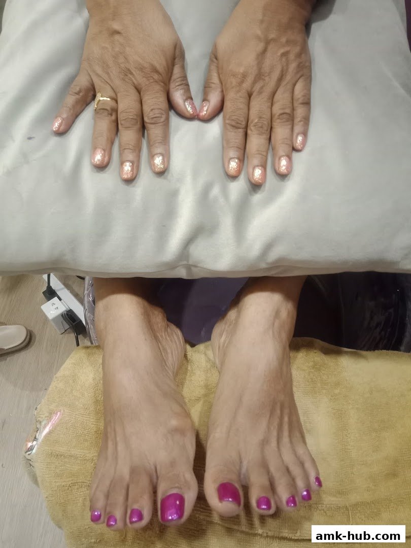 A close-up of hands and feet with freshly painted nails, showcasing vibrant colors and glitter.