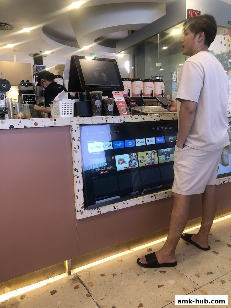 A customer pays at a modern beverage counter with a digital display.