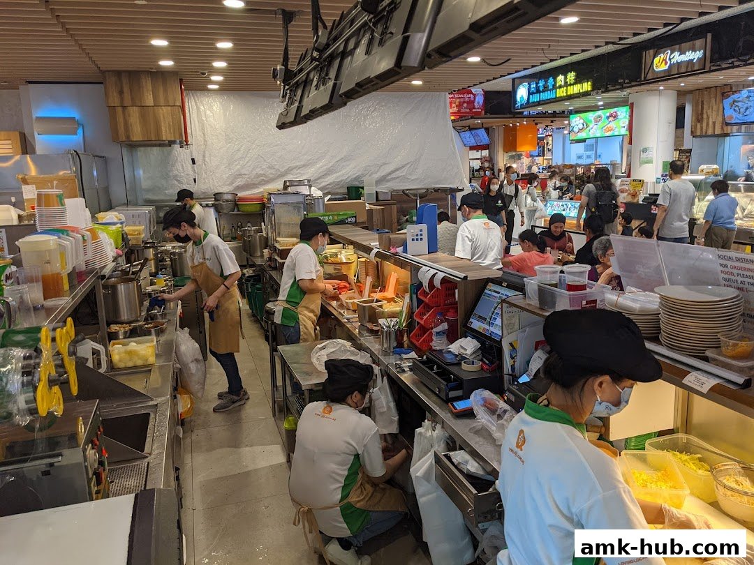 Staff preparing food behind the counter at a busy food stall in a mall.