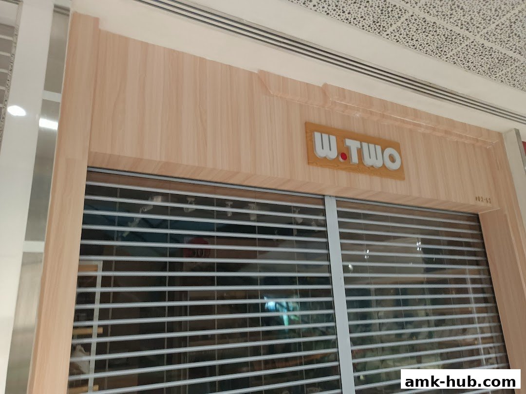The storefront of W.TWO, featuring a wooden facade and a closed roller shutter.