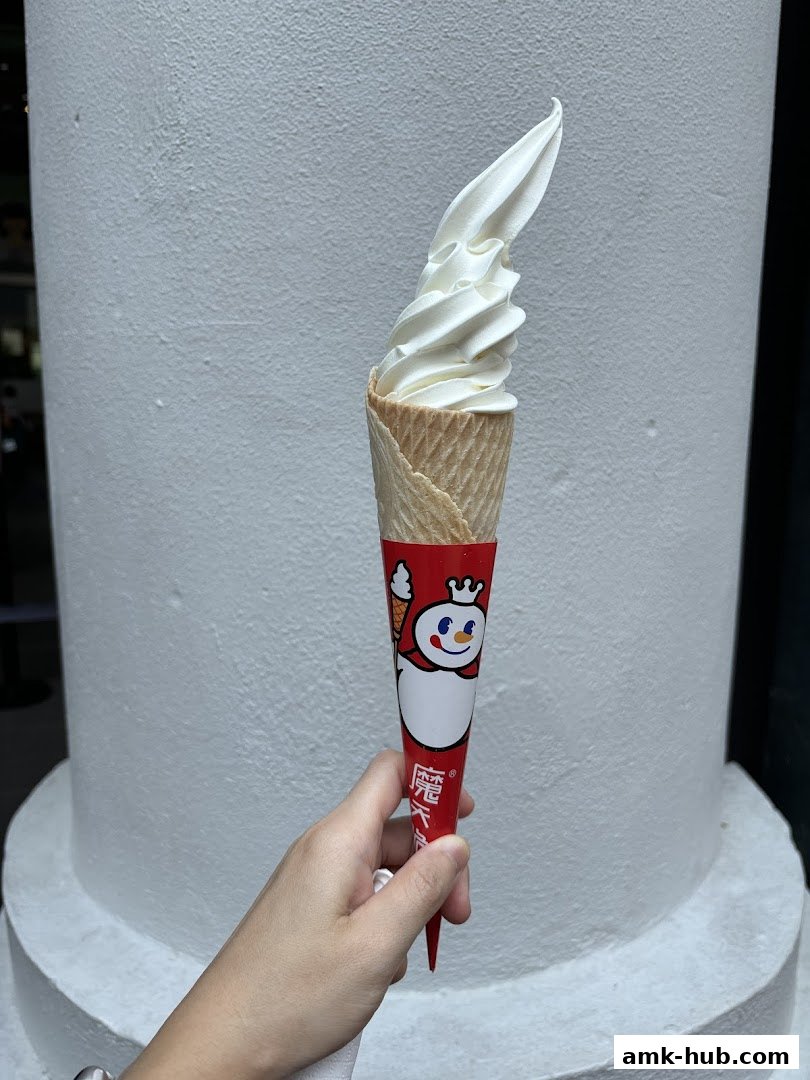 A hand holds a soft-serve ice cream cone with the MIXUE logo.