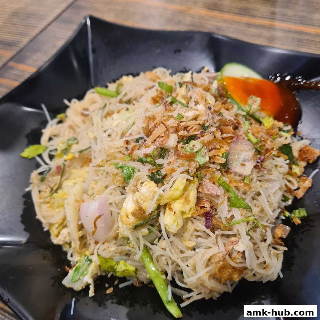 A close-up shot of a plate of stir-fried noodles with vegetables and crispy fried onions.