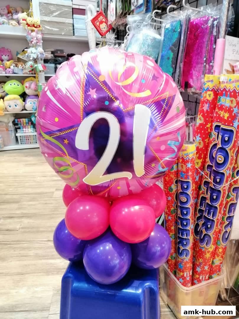 A festive balloon arrangement with the number 21, surrounded by party poppers and other party supplies.