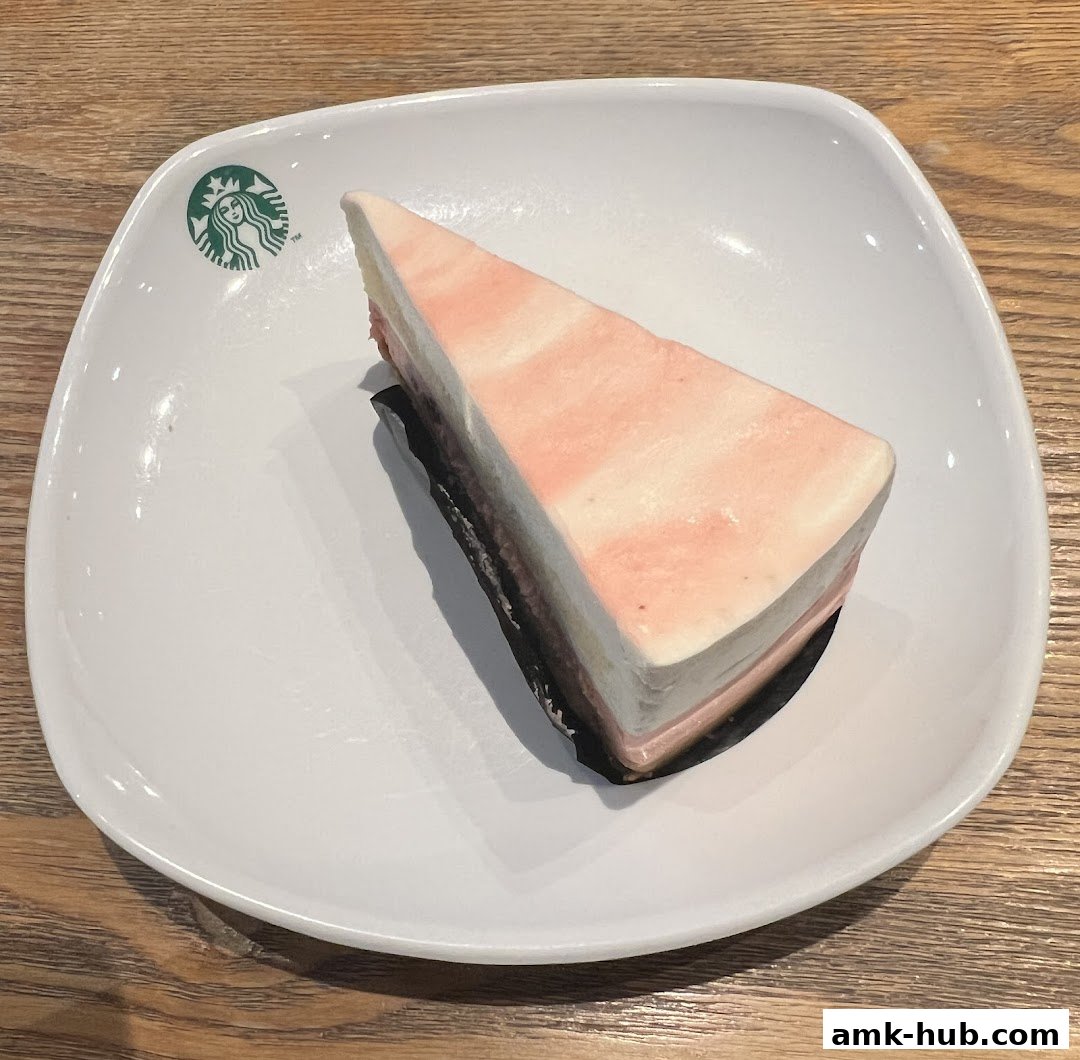 A slice of layered cake with pink and white frosting on a white plate.