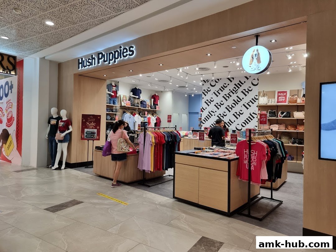 The entrance of a Hush Puppies store displaying clothing, accessories, and sale signs.