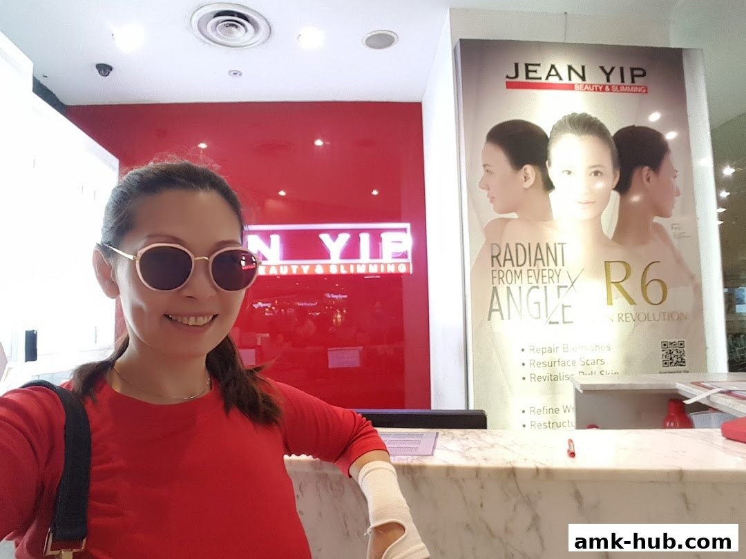 A woman smiles at the camera in front of a Jean Yip Beauty & Slimming shop.