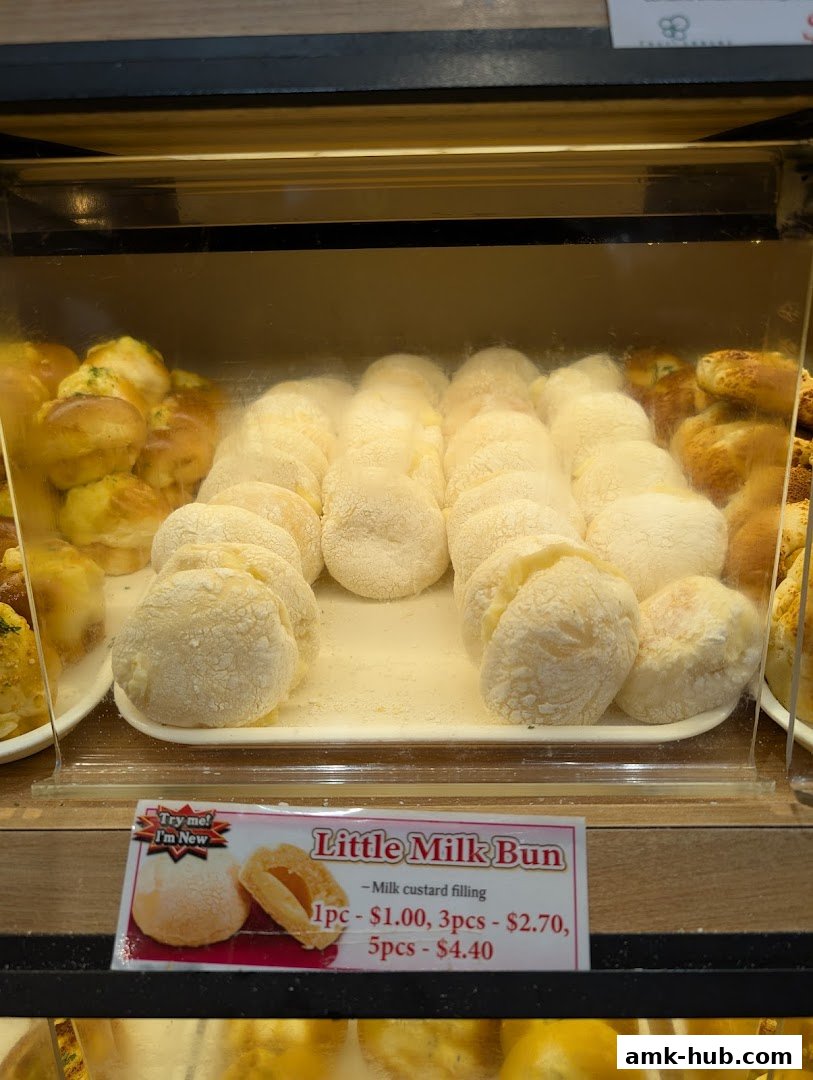 A display case filled with freshly baked buns, featuring a sign for 'Little Milk Bun'.