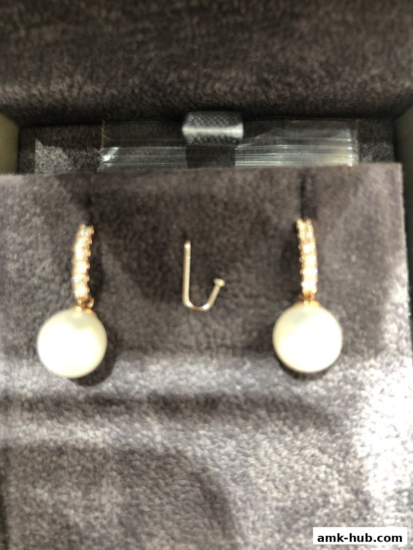 A pair of pearl and diamond drop earrings displayed in a velvet jewelry box.
