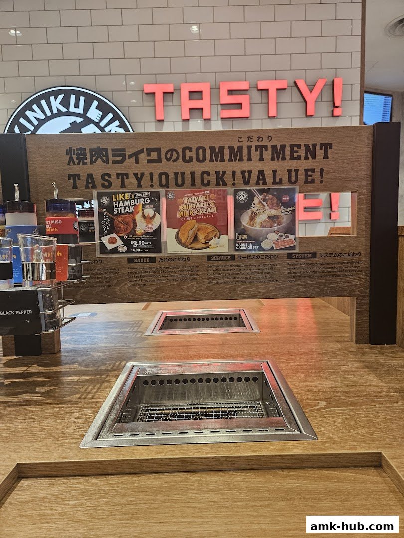 Interior view of Yakiniku Like with grill stations and menu displays featuring Japanese dishes.