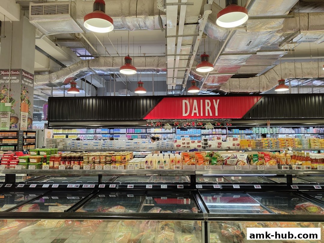 A wide aisle in a supermarket featuring a prominent 'DAIRY' sign above refrigerated shelves stocked with various products.